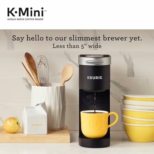 Keurig K-Mini coffee maker brewing into a yellow mug with kitchen items nearby.